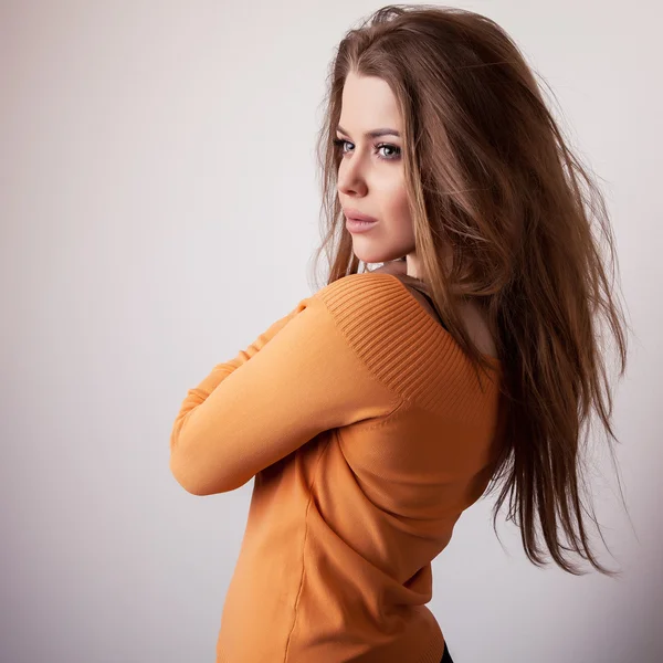 Young sensual & beauty model girl iin casual orange sweater pose in studio. — Stock Photo, Image