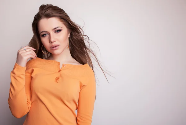 Young sensual & beauty model girl iin casual orange sweater pose in studio. — Stock Photo, Image