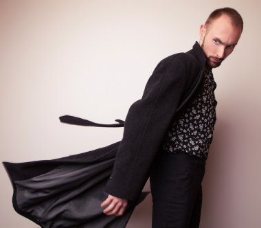 Uzun yün ceket zarif genç yakışıklı adam. Studio moda portre.