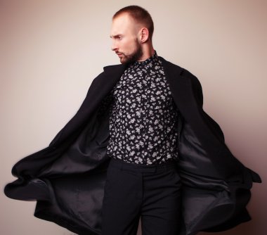 Uzun yün ceket zarif genç yakışıklı adam. Studio moda portre.