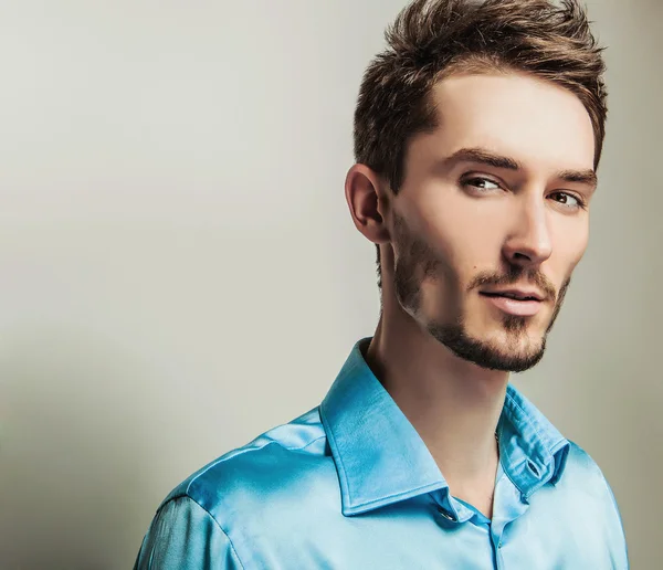 Elegante jonge knappe man in blauwe zijde shirt. Studio mode portret. — Stockfoto