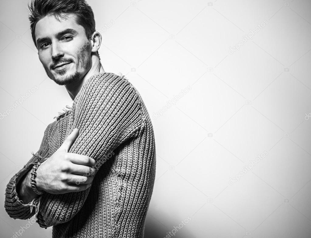 Black-white studio portrait of young handsome man in knitted sweater. Close-up photo.