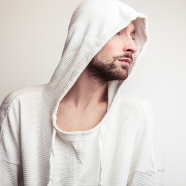 Stüdyo portre hood ile beyaz kazaklı genç yakışıklı adamın.