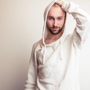 Stüdyo portre hood ile beyaz kazaklı genç yakışıklı adamın.