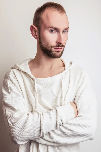 Studioporträt eines jungen gutaussehenden Mannes in weißem Pullover mit Kapuze. — Stockfoto