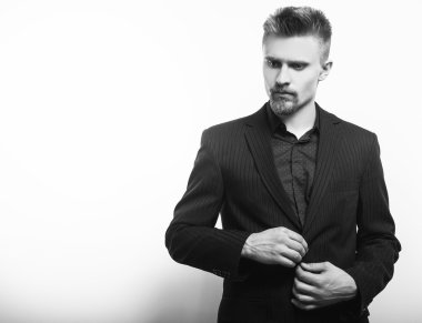 Siyah kostümlü zarif genç yakışıklı adam. Siyah-beyaz studio moda portre.