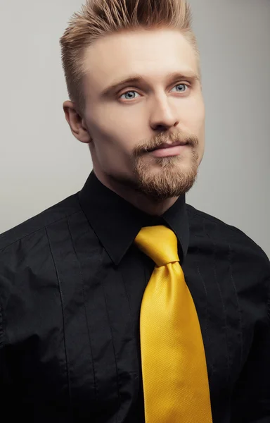 Elegante jonge knappe man in zwarte shirt & gele stropdas. Studio mode portret. — Stockfoto