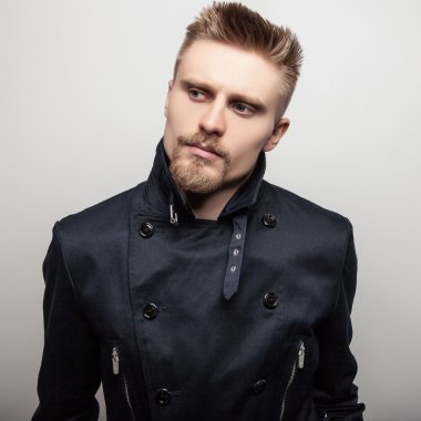 Siyah montlu zarif genç yakışıklı adam. Studio moda portre.