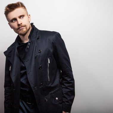 Siyah montlu zarif genç yakışıklı adam. Studio moda portre.