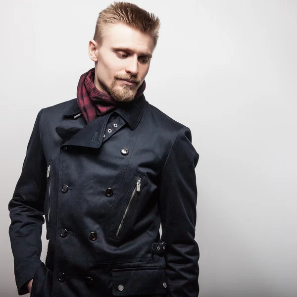 Eleganter junger gutaussehender Mann in schwarzem Mantel. Modeporträt im Studio. — Stockfoto