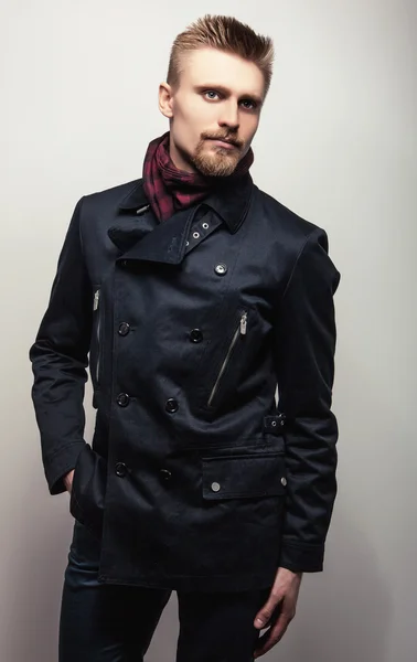 Eleganter junger gutaussehender Mann in schwarzem Mantel. Modeporträt im Studio. — Stockfoto