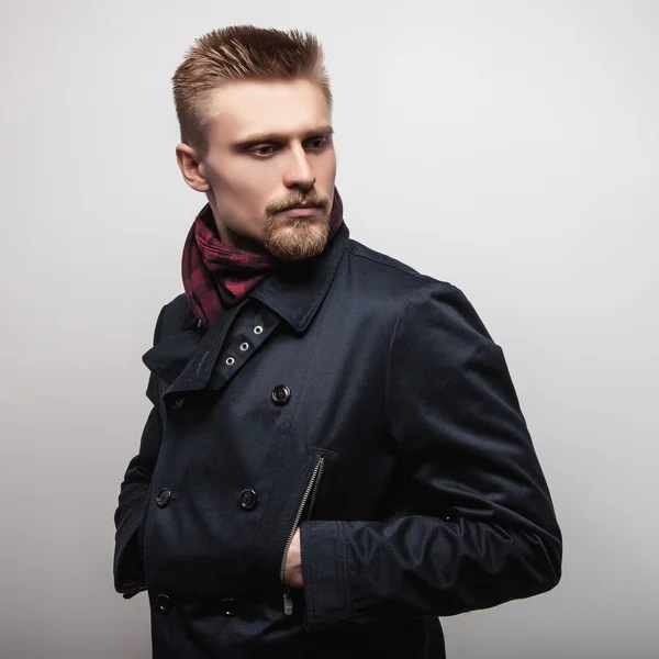 Elegantní mladý pohledný muž v černém kabátě. Portrét módní Studio. — Stock fotografie