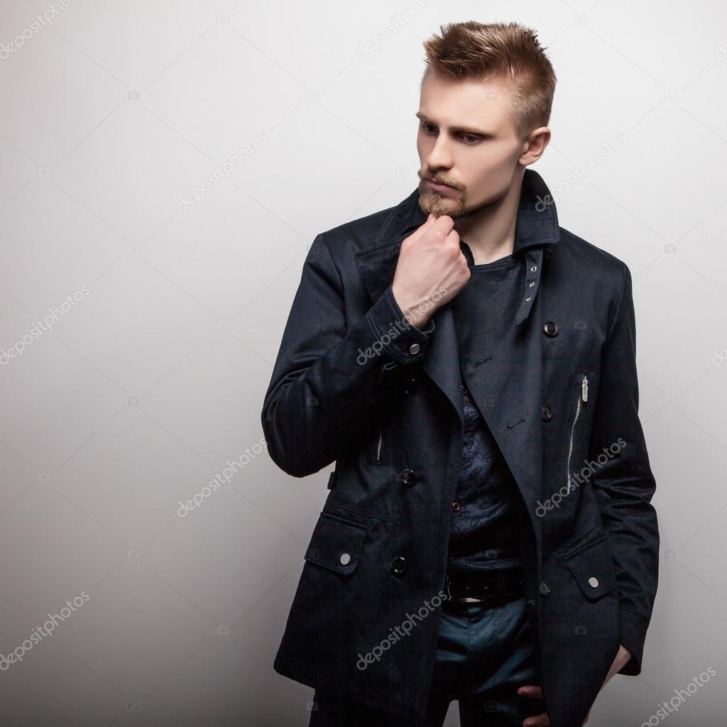 Elegant young handsome man in black coat. Studio fashion portrait.