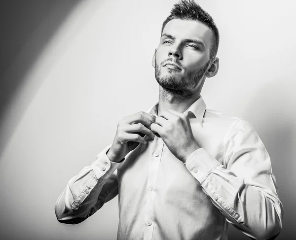 Eleganter junger gutaussehender ernster Mann in weißem Hemd. Schwarz-weißes Modeporträt im Studio. — Stockfoto