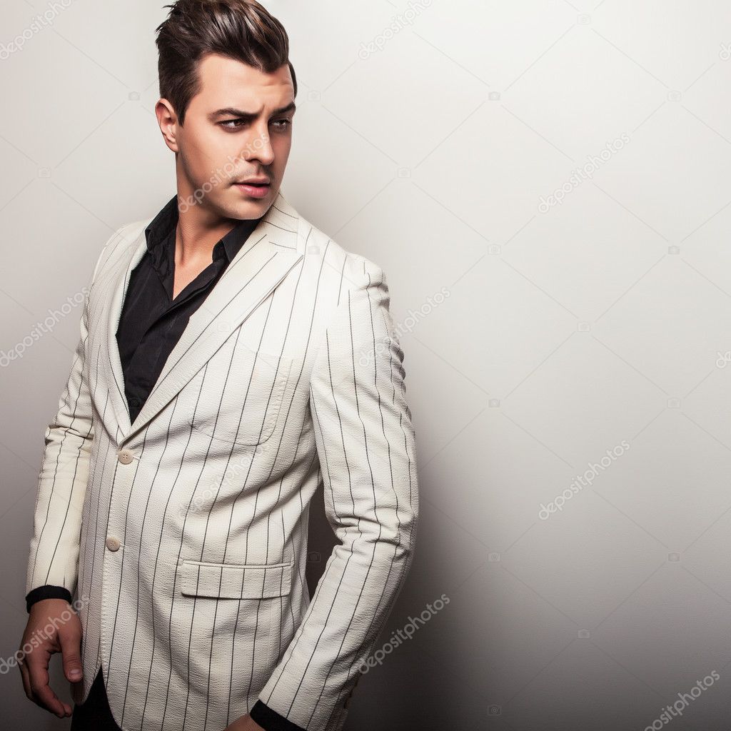 Elegant young handsome man in white costume. Studio fashion portrait.