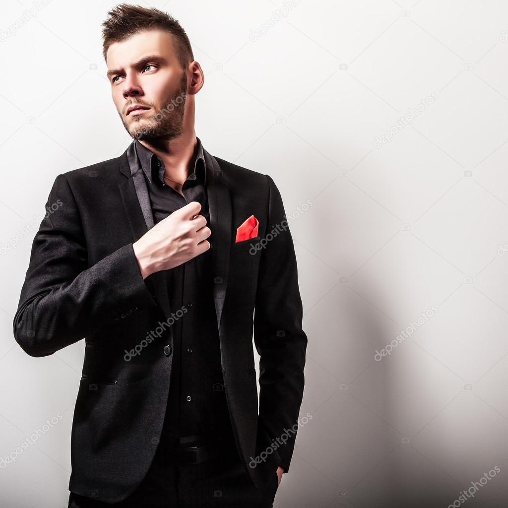 Elegant young handsome serious man in black costume. Studio fashion portrait.