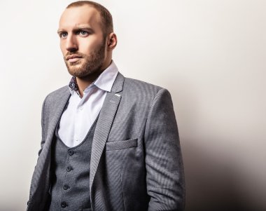 Gri kostümlü zarif genç yakışıklı adam. Studio moda portre.