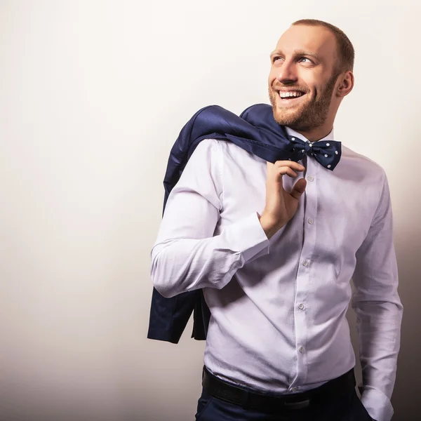 Homem bonito jovem elegante em traje azul escuro e gravata borboleta. Estúdio retrato de moda . — Fotografia de Stock