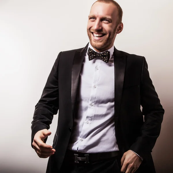 Elégant jeune homme beau et souriant en costume noir. Studio portrait de mode . — Photo