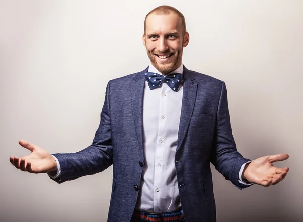 Eleganter junger gutaussehender Mann in dunkelblauem Kostüm & Fliege. Modeporträt im Studio. — Stockfoto