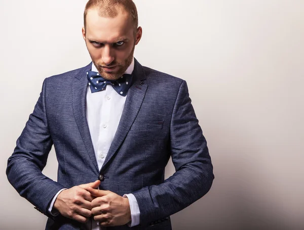 Homem bonito jovem elegante em traje azul escuro e gravata borboleta. Estúdio retrato de moda . — Fotografia de Stock