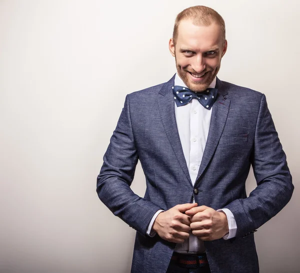 Eleganter junger gutaussehender Mann in dunkelblauem Kostüm & Fliege. Modeporträt im Studio. — Stockfoto