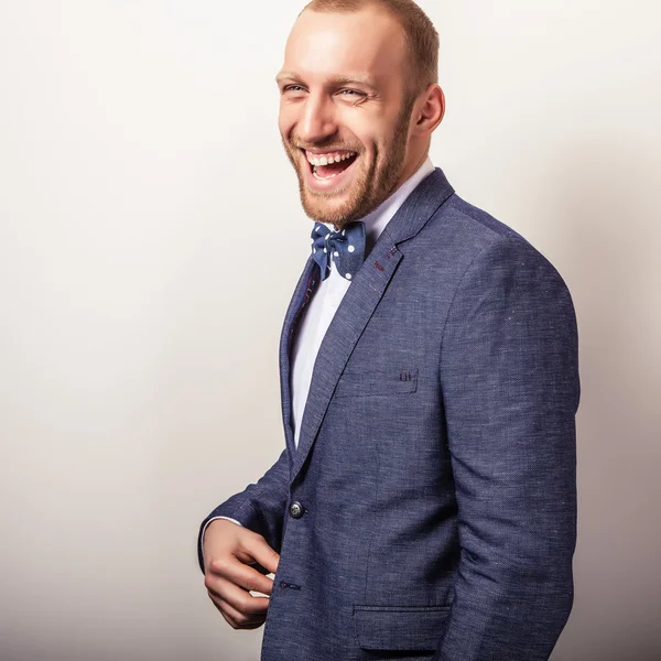 Eleganter junger gutaussehender Mann in dunkelblauem Kostüm & Fliege. Modeporträt im Studio. — Stockfoto