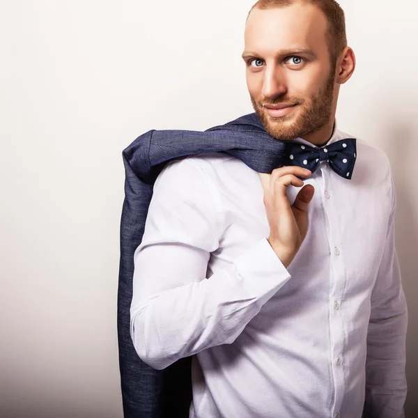 Eleganter junger gutaussehender Mann in weißem Hemd mit Fliege und dunkelblauem Kostüm. Modeporträt im Studio. — Stockfoto