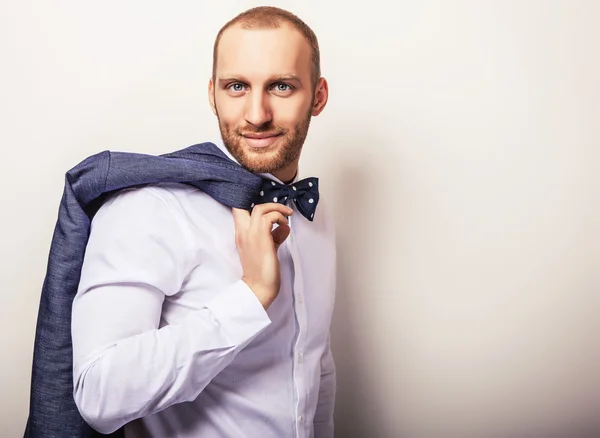 Eleganter junger gutaussehender Mann in weißem Hemd mit Fliege und dunkelblauem Kostüm. Modeporträt im Studio. — Stockfoto