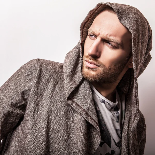 Studio portrait of young handsome man in casual cape with a hood. Close-up photo. — Stock Photo, Image