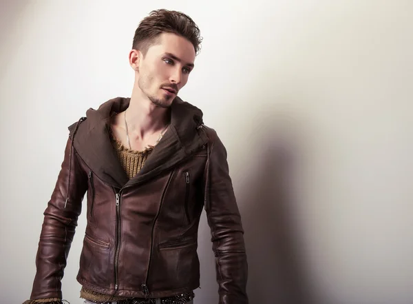 Attractive young man in a brown leather jacket pose in studio. — Stock Photo, Image