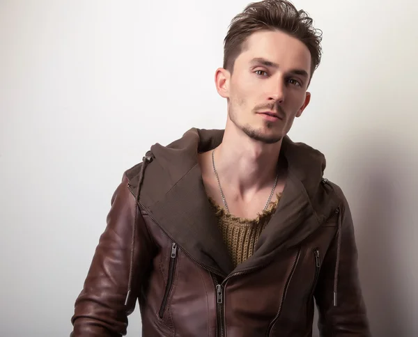 Jeune homme attrayant dans une pose de veste en cuir marron en studio . — Photo