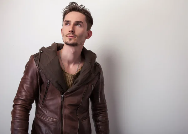 Привлекательный молодой человек в коричневой кожаной куртке позирует в студии . — стоковое фото