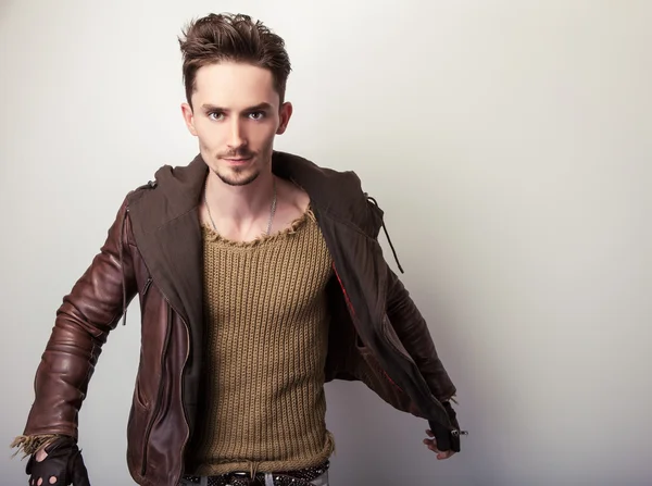 Attractive young man in a brown leather jacket pose in studio. — Stock Photo, Image