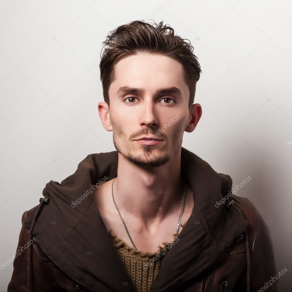 Attractive young man in a brown leather jacket pose in studio.