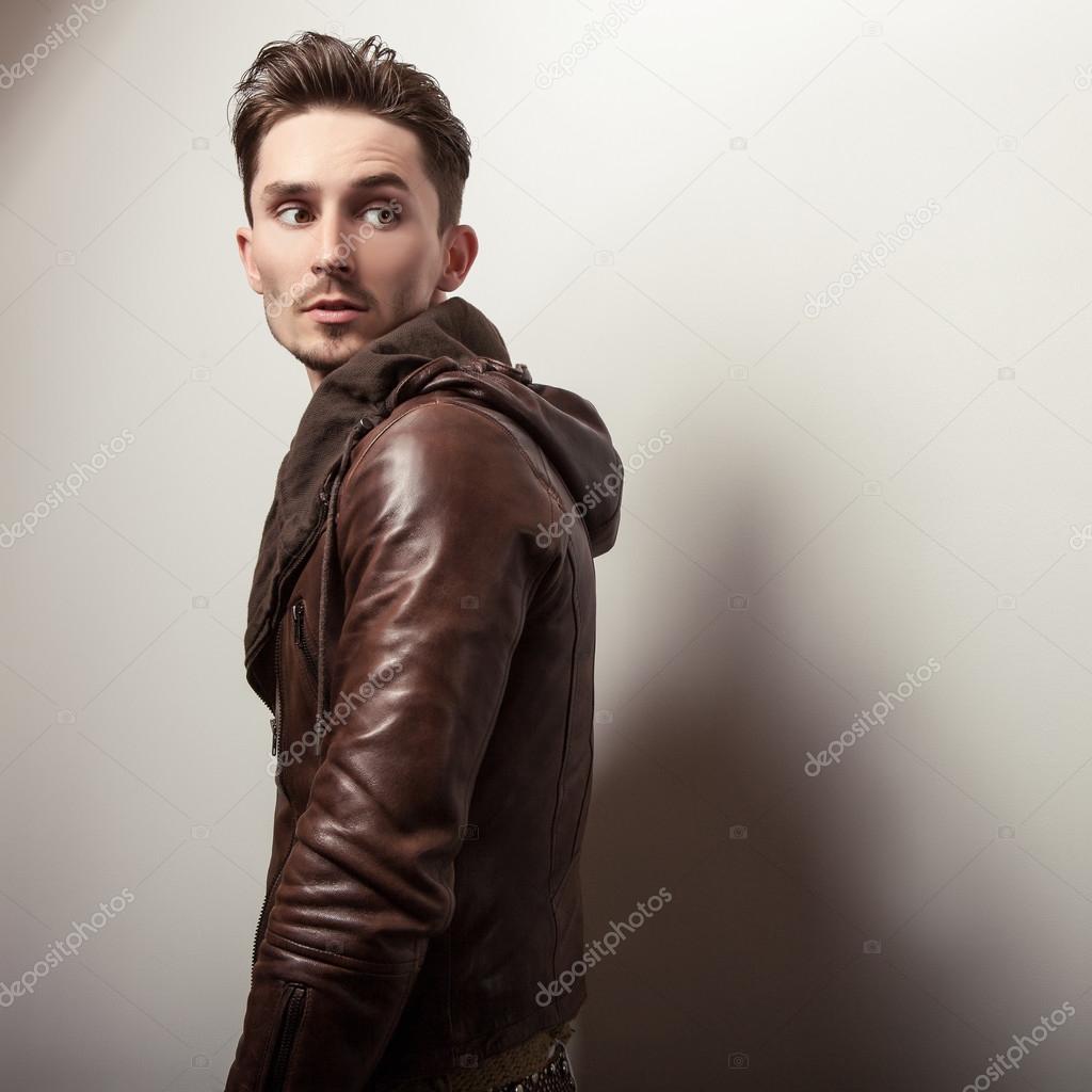 Attractive young man in a brown leather jacket pose in studio.