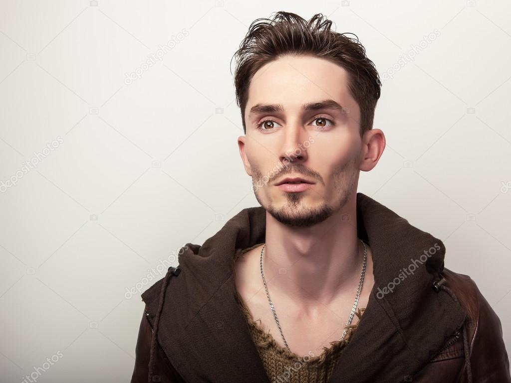 Attractive young man in a brown leather jacket pose in studio.