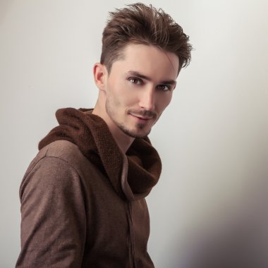 Çekici bir genç adam kahverengi süveter poz Studio.