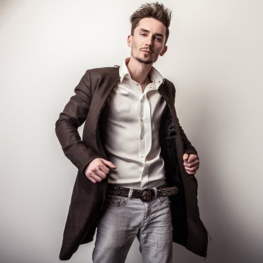 Uzun şık ceket zarif genç yakışıklı adam. Studio moda portre.