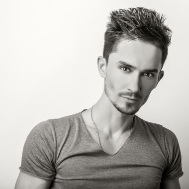 Portrait of young handsome man in grey t-shirt. Sepia studio photo.