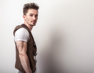 Attractive young man in a brown vest and white t-shirt pose in studio.