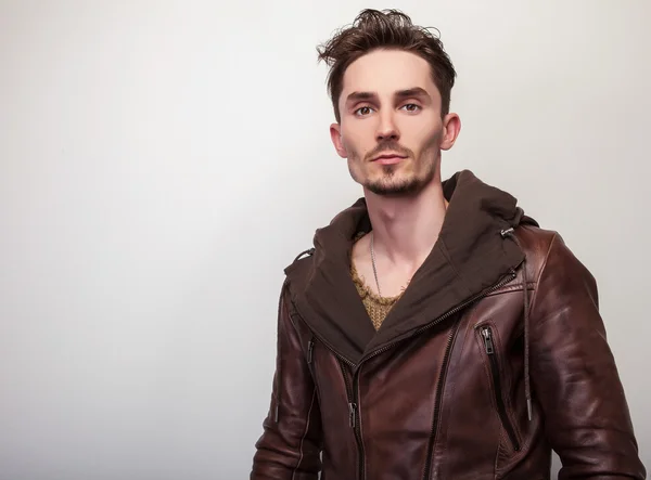 Atractivo joven en una pose chaqueta de cuero marrón en el estudio . — Foto de Stock