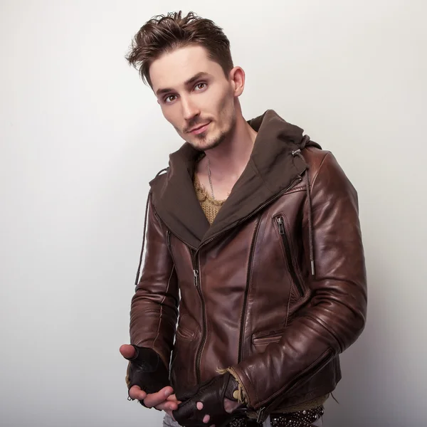 Stanowią atrakcyjny młody człowiek w brązowy skórzana kurtka w studio. — Zdjęcie stockowe