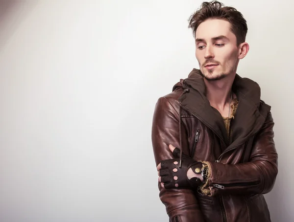 Привлекательный молодой человек в коричневой кожаной куртке позирует в студии . — стоковое фото