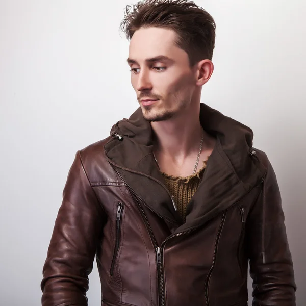 Привабливий молодий чоловік в позі коричневої шкіряної куртки в студії . — стокове фото