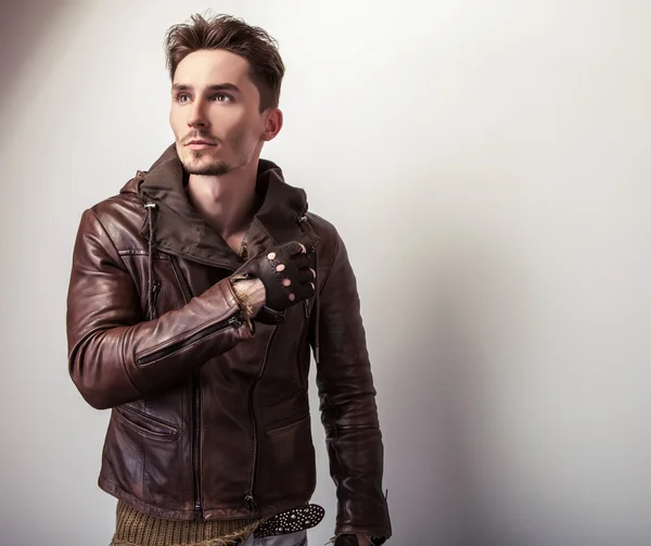 Attractive young man in a brown leather jacket pose in studio. — Stock Photo, Image