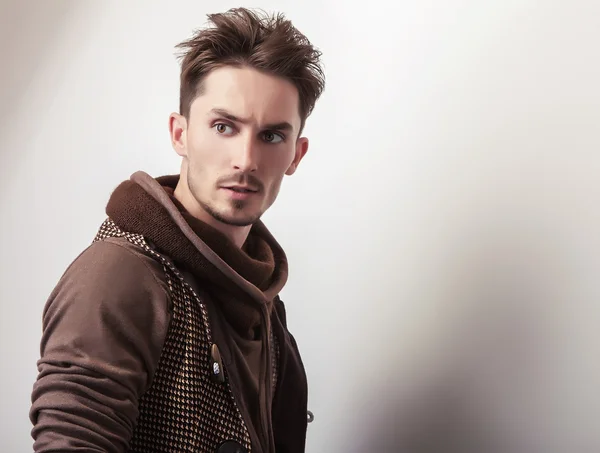 Attraente giovane uomo in una posa maglione marrone in studio . — Foto Stock