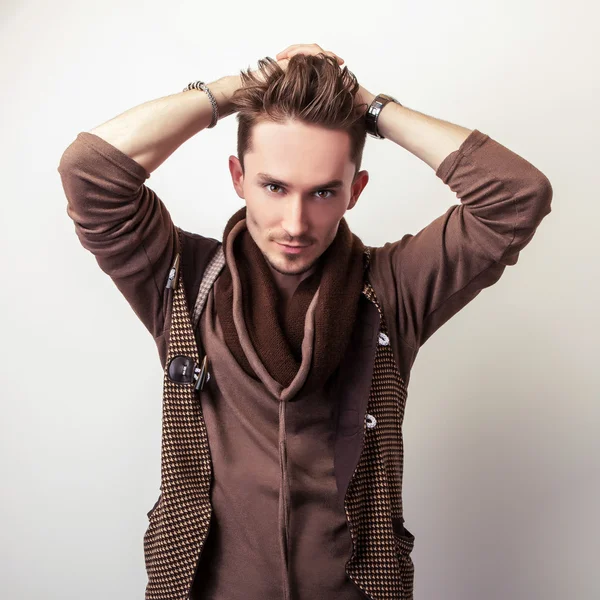 Attraktiv ung man i en brun tröja pose i studio. — Stockfoto