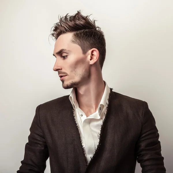 Elegante jovem homem bonito em casaco longo e elegante. Estúdio retrato de moda . — Fotografia de Stock