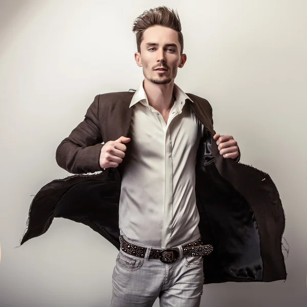 Elegant unga stilig man i lång snygg jacka. Studio mode porträtt. — Stockfoto